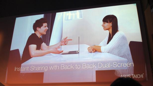 Ein Mann und eine Frau sitzen an einem Tisch mit einem ASUS TAICHI Laptop und unterhalten sich.