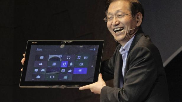 Ein lächelnder Mann präsentiert ein ASUS-Tablet mit Windows-Oberfläche.