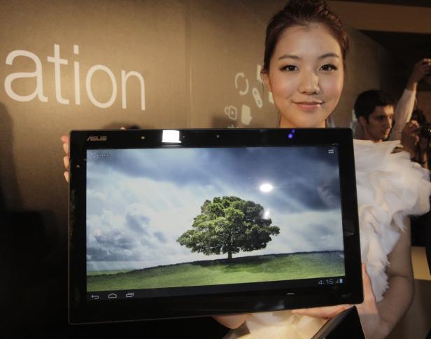 Eine Frau präsentiert ein ASUS-Tablet, auf dessen Bildschirm ein Baum in einer Landschaft zu sehen ist.