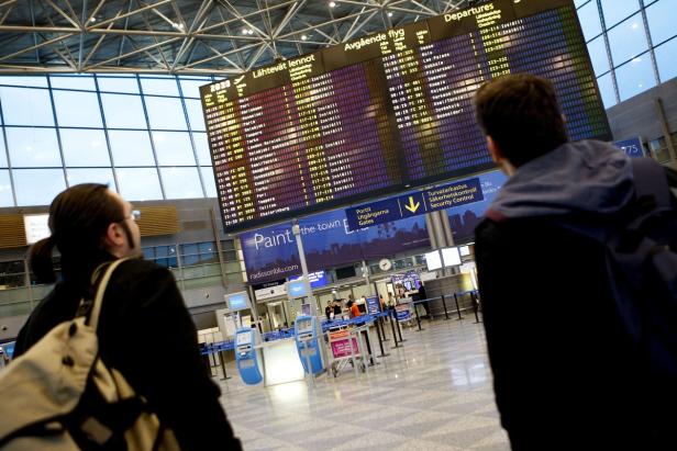 Reisende betrachten die Abflugtafel in einem Flughafen-Terminal.