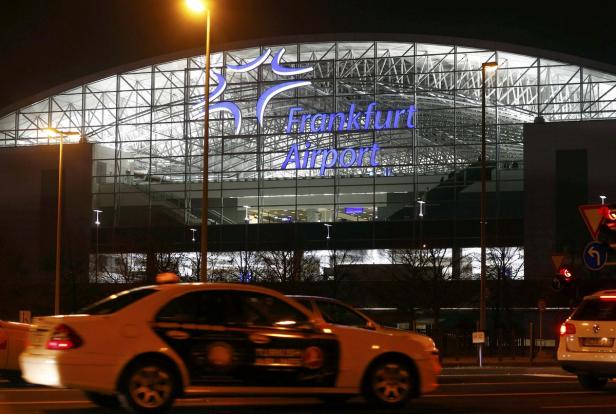 Der Frankfurter Flughafen bei Nacht mit Taxis im Vordergrund.