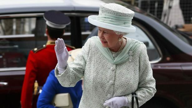 Königin Elisabeth II. winkt in einem hellgrünen Kostüm und Hut.