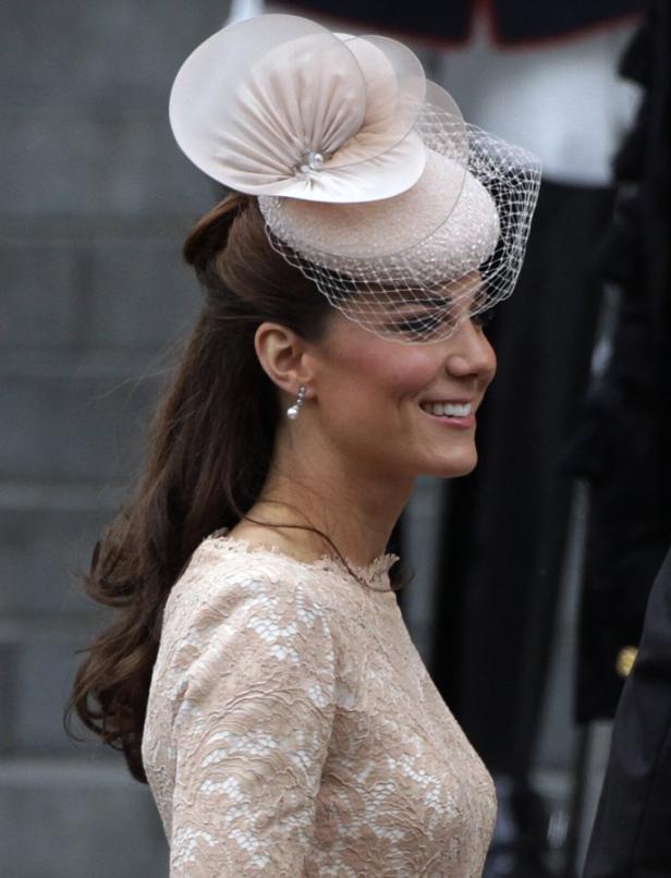 Kate Middleton mit einem eleganten Hut und einem Spitzenkleid.