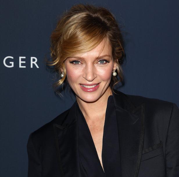 Uma Thurman lächelt in einem schwarzen Blazer.