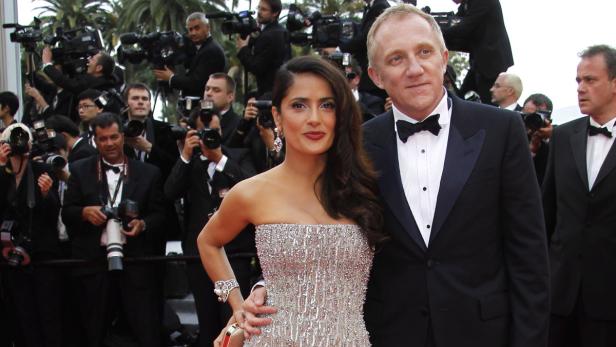 Salma Hayek und François-Henri Pinault posieren vor einer Wand von Fotografen.