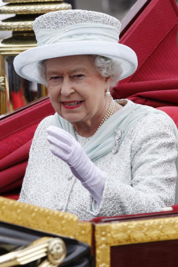 Königin Elisabeth II. winkt in einem hellblauen Kleid und Hut.