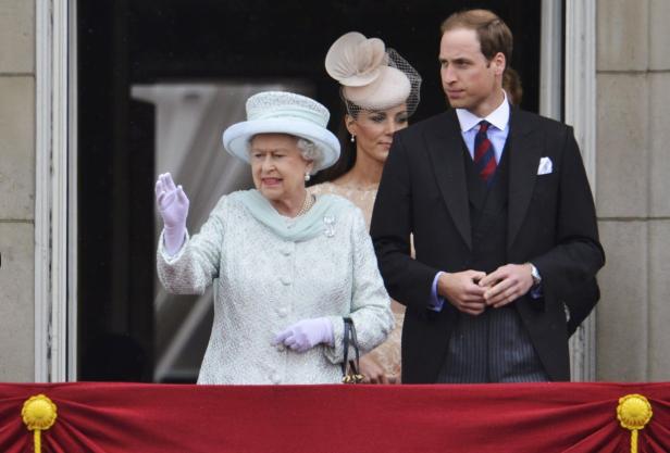Königin Elizabeth II. winkt mit Prinz William und Kate Middleton auf einem Balkon.