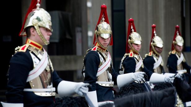 Eine Reihe von berittenen Gardesoldaten in Paradeuniformen und Helmen.