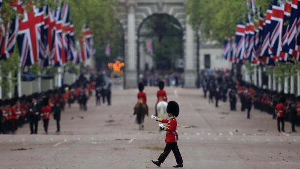 Ein Gardesoldat marschiert auf der von britischen Flaggen gesäumten Straße in London.