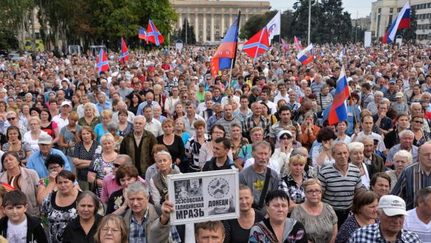 Eine große Menschenmenge demonstriert mit Flaggen in einer Stadt.