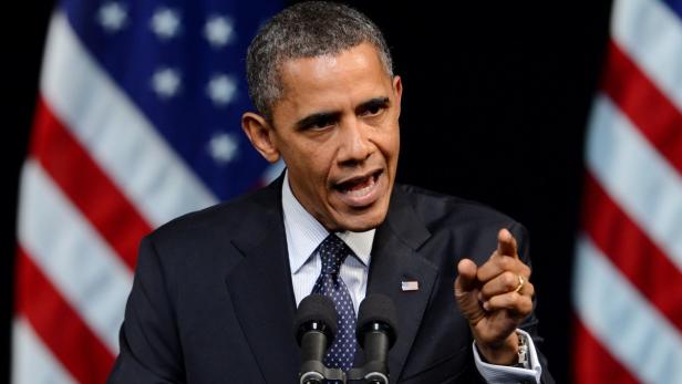 Barack Obama spricht vor amerikanischen Flaggen.