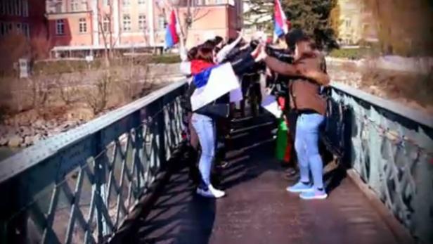 Eine Gruppe von Menschen steht mit Flaggen auf einer Brücke.