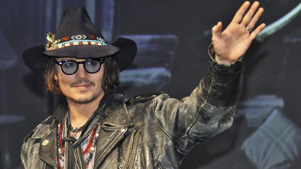 Johnny Depp mit Hut und Brille winkt in die Kamera.
