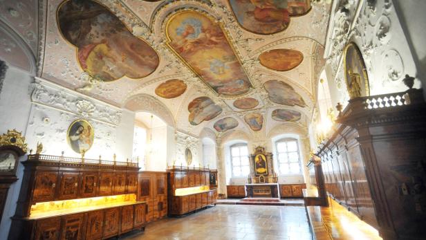 Ein reich verzierter Raum mit Gemälden an der Decke und kunstvollen Holzmöbeln.