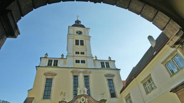 Blick durch einen Torbogen auf einen Kirchturm mit Uhr.