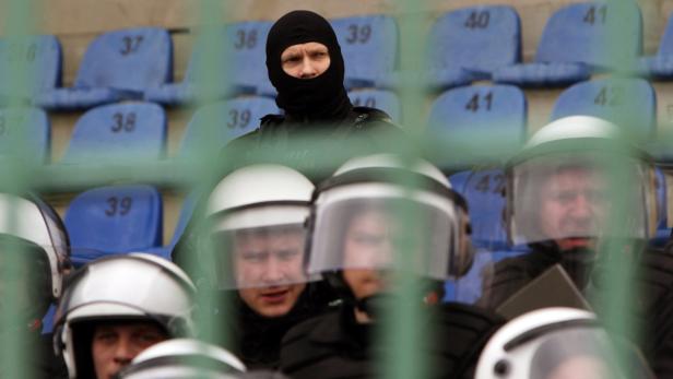 Polizisten in Schutzkleidung sitzen auf nummerierten Sitzen in einem Stadion.