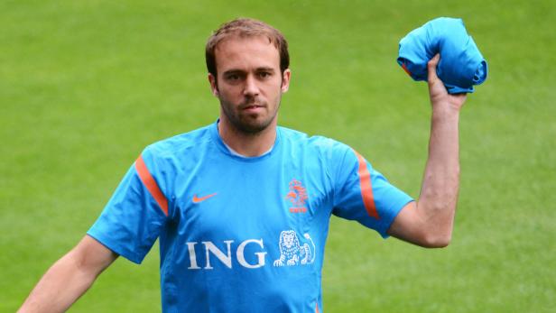 Ein Mann im blauen Trikot der niederländischen Nationalmannschaft hält ein Trikot in der Hand.