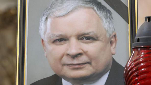 Ein gerahmtes Porträt von Lech Kaczyński neben einer roten Grabkerze.