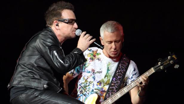 Bono von U2 singt, während ein anderer Mann Bassgitarre spielt.