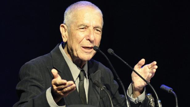 Leonard Cohen spricht bei einer Veranstaltung in ein Mikrofon.