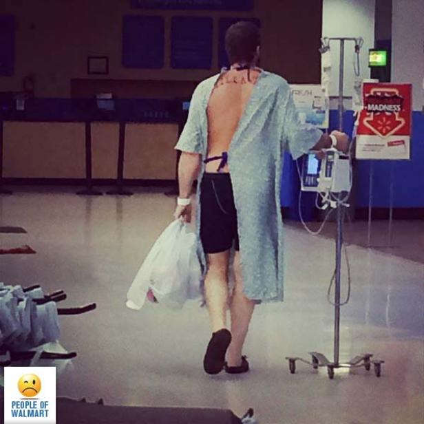 Ein Mann im Krankenhaushemd schiebt einen Infusionsständer durch einen Walmart.