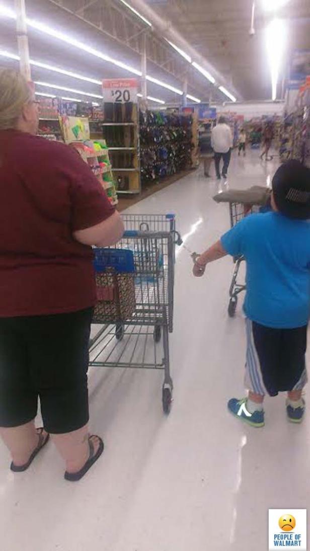 Ein Kind führt eine Frau mit Handschellen in einem Walmart-Geschäft an einem Einkaufswagen.