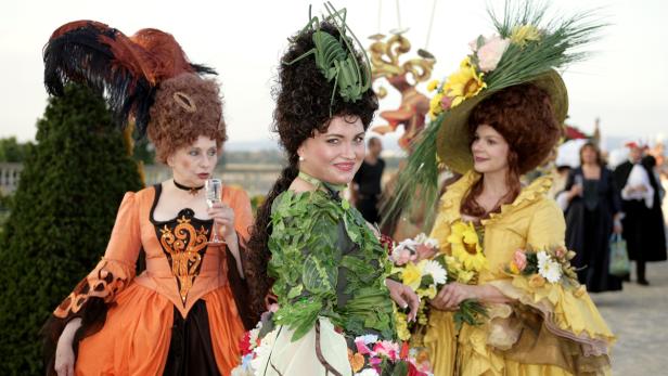Drei Frauen in fantasievollen Rokoko-Kostümen posieren im Freien.