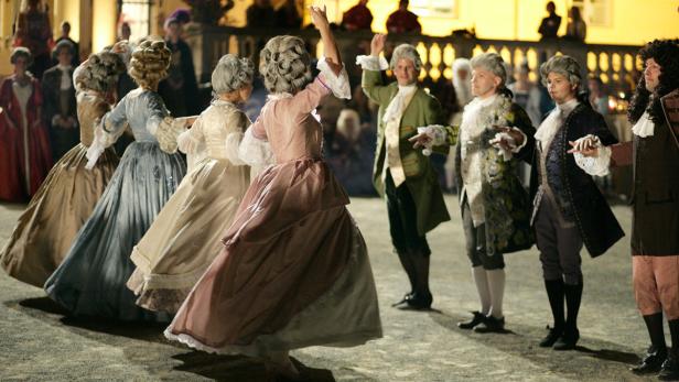 Eine Gruppe von Menschen in historischen Kostümen tanzt im Freien.