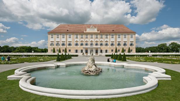 Schloss Hof mit einem Brunnen im Vordergrund an einem sonnigen Tag.
