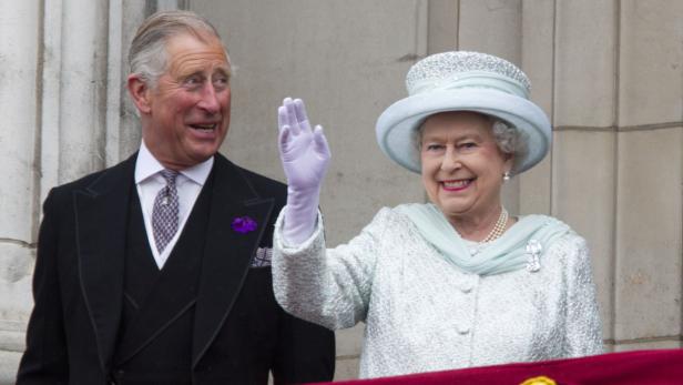 König Charles und Königin Elizabeth winken von einem Balkon.