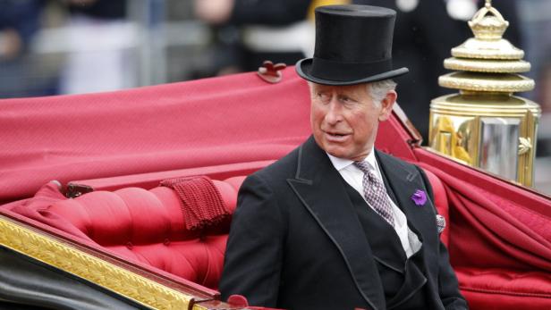 König Charles III. in einer Kutsche mit roter Innenausstattung.