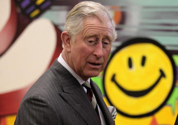 König Charles III. vor einem Wandbild mit einem Smiley.