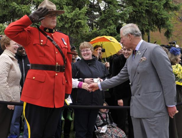 Prinz Charles schüttelt einem kanadischen Mountie die Hand, der salutiert.