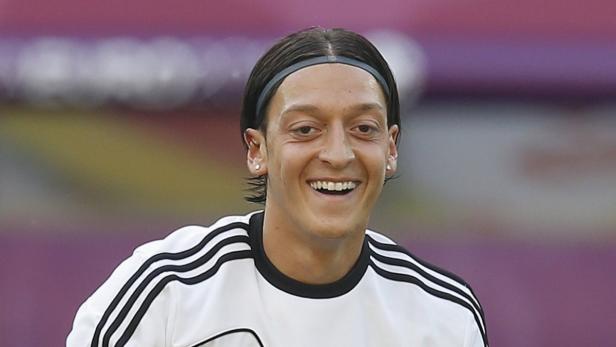 Mesut Özil lächelt in einem Trikot mit schwarzen Streifen.