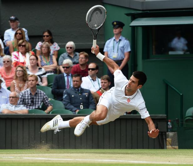 Novak Đoković macht einen Hechtsprung auf einem Tennisplatz.