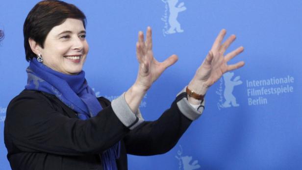 Isabelle Huppert posiert auf den Internationalen Filmfestspielen Berlin mit erhobenen Händen.