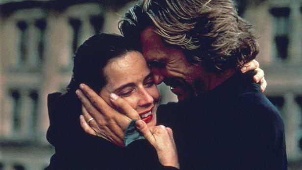 Ein Mann und eine Frau umarmen sich innig vor einem Gebäude.