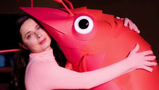 Eine Frau umarmt eine große, rote Krabbe aus Papier.