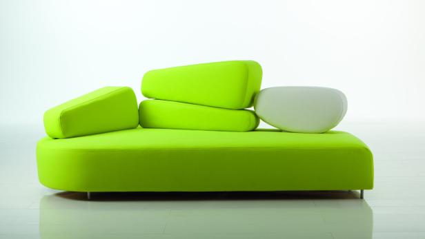 Ein modernes Sofa in Grün und Weiß mit ungewöhnlicher Kissenanordnung.