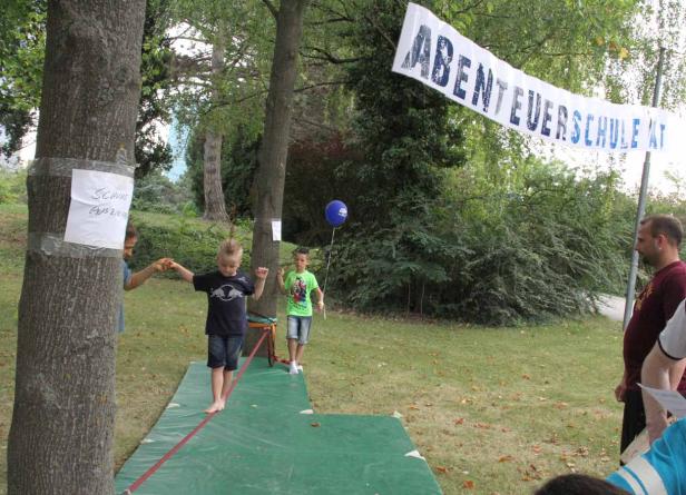 Ein Junge balanciert barfuß auf einer Slackline bei der „Abenteuerschule AT“.