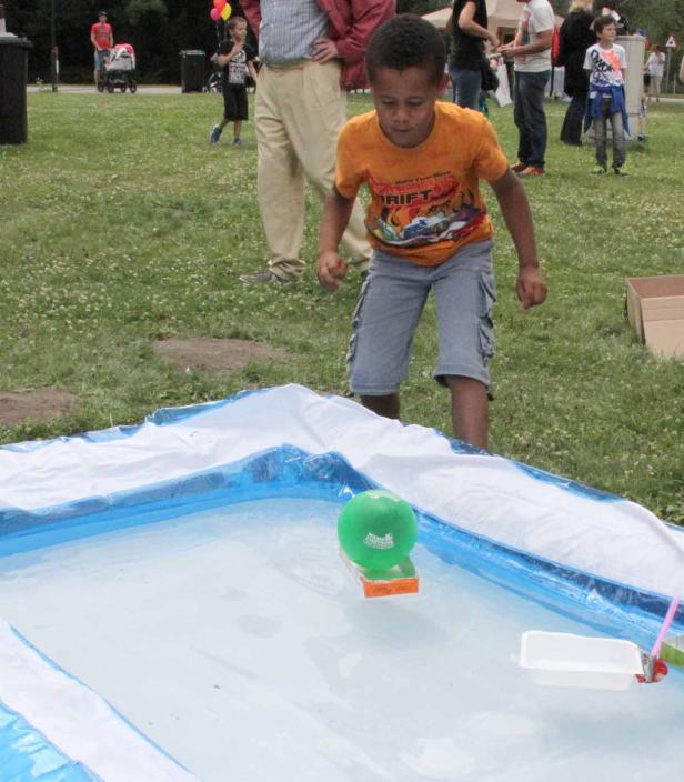 Ein Junge spielt mit einem kleinen Boot in einem Planschbecken.
