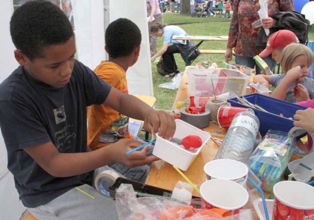 Kinder basteln an einem Tisch mit verschiedenen Materialien wie Papier, Kleber und Stiften.