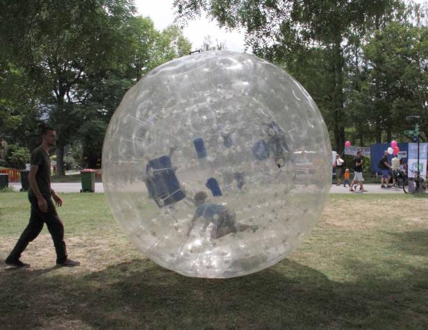 Eine Person befindet sich in einer riesigen, transparenten Zorbing-Kugel im Freien.