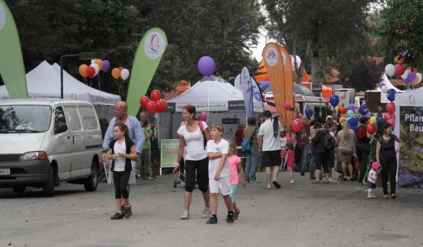 Eine Familie schlendert über eine belebte Festveranstaltung mit Ballons und Ständen.