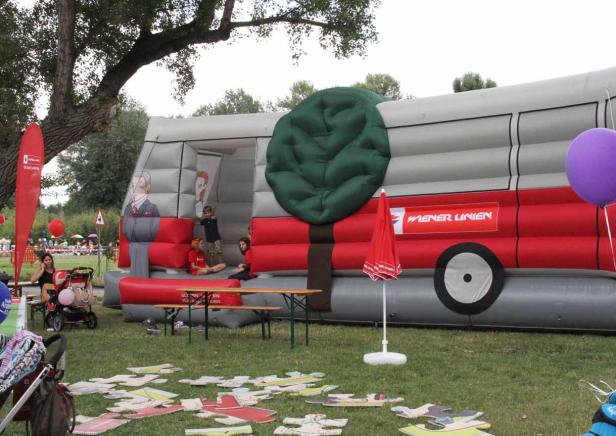 Ein Hüpfburg-Bus der Wiener Linien steht auf einer Wiese, Kinder spielen davor.