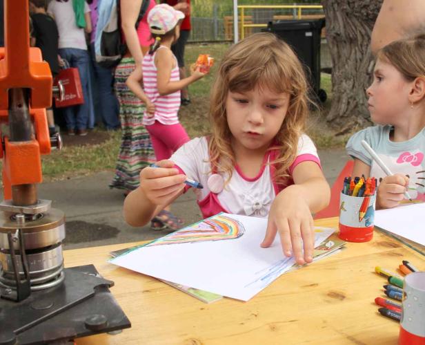Ein Mädchen zeichnet mit Buntstiften auf einem Blatt Papier.