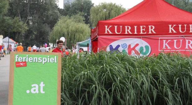 Ein Stand des „Ferienspiel WienXtra“ mit einem roten Kurier-Zelt im Hintergrund.
