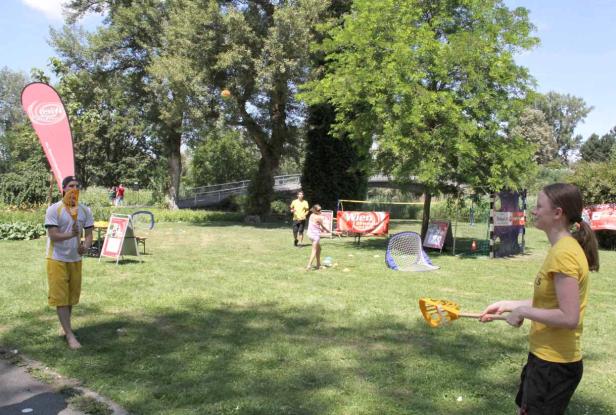 Menschen spielen im Park mit Schlägern und Bällen.