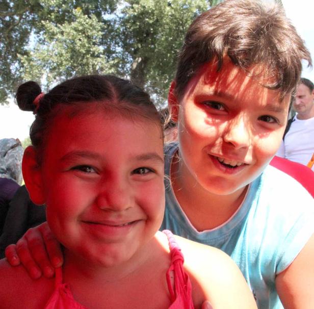 Zwei lächelnde Kinder posieren für ein Foto im Freien.