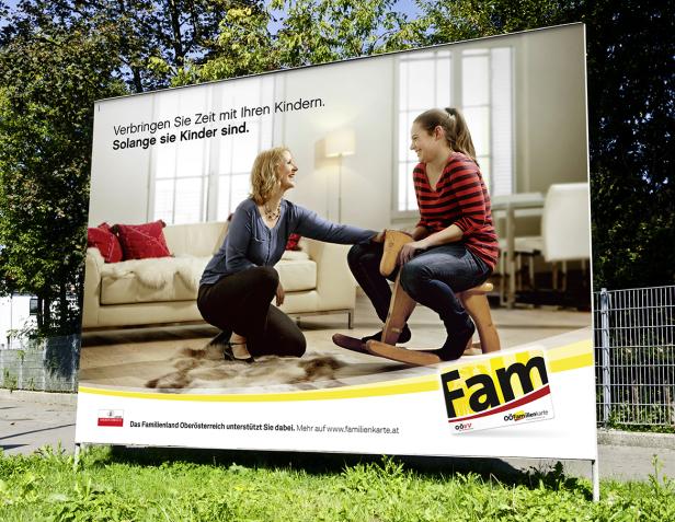 Eine Mutter und ihre Tochter spielen mit einem Schaukelpferd auf einer Werbetafel.